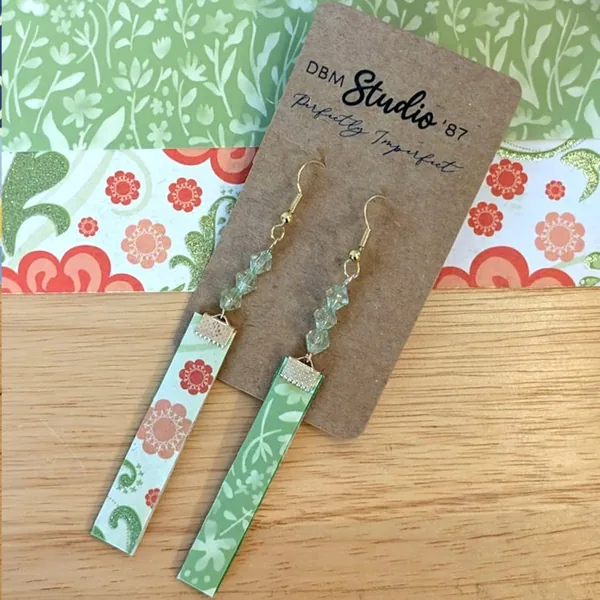 Floral earrings with green, orange and red flowers on the front, green and cream flowers on the back. Green beads and gold metals.